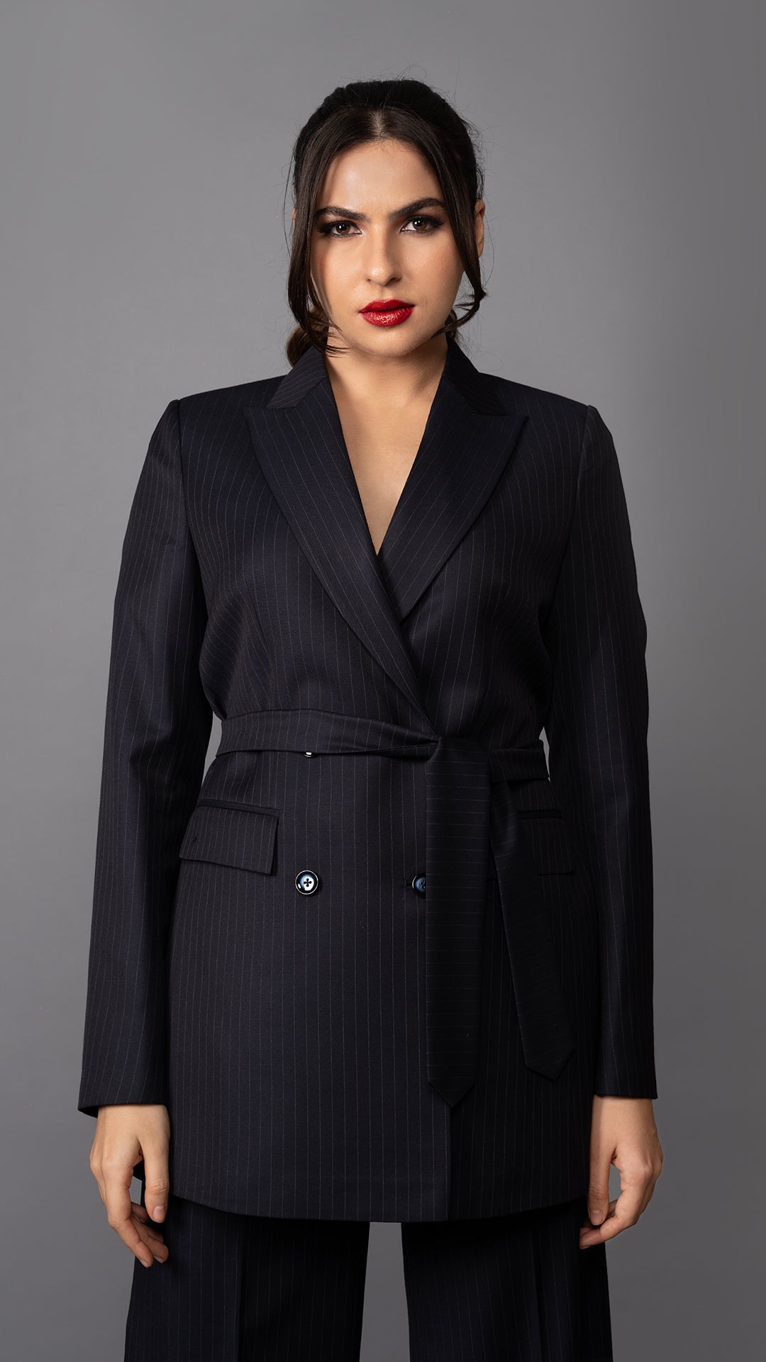 A stylish blue pinstripe blazer with a flattering belted waist, structured peak lapel, and tailored fit for a commanding look.