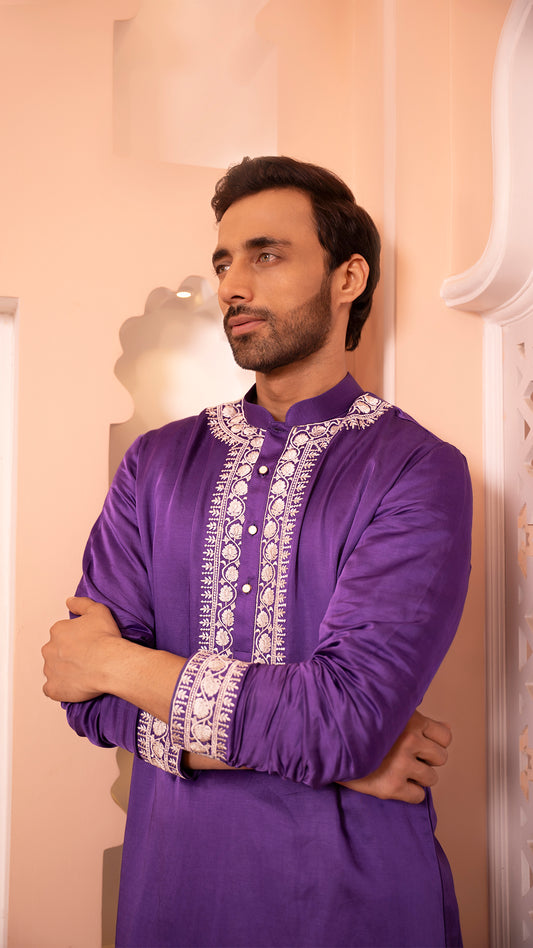 Man wearing a purple embroidered kurta against a neutral background