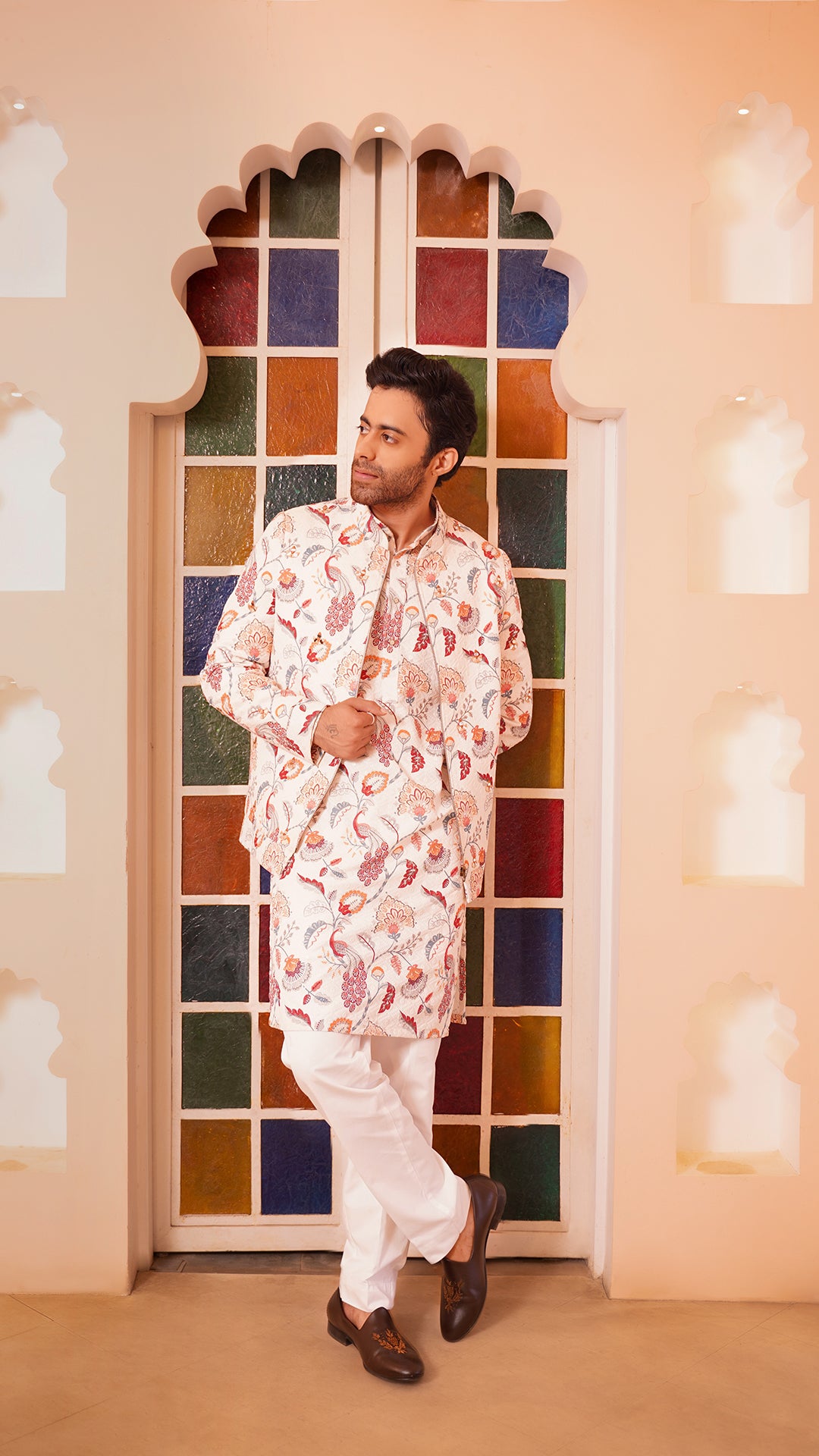 Man in animal motif bomber jacket set standing in front of a colorful stained glass window.