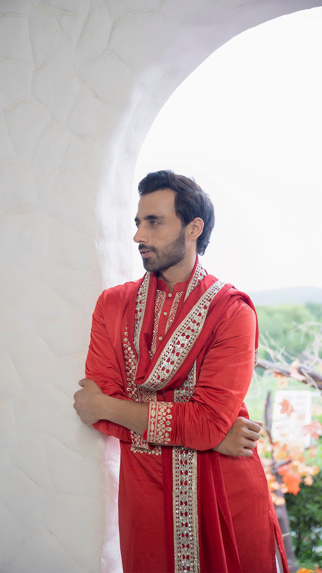 Man wearing a red Kurta with white patiala against a blurred outdoor background