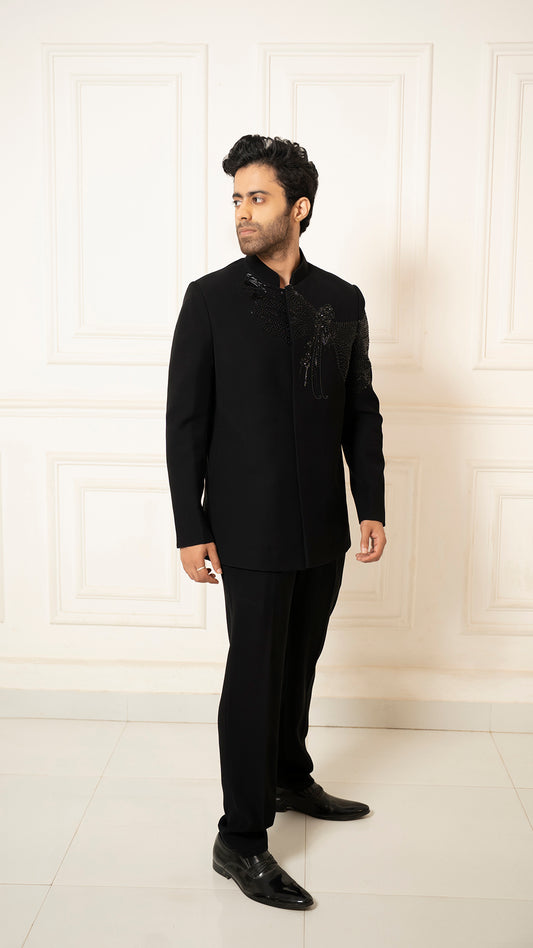 Man wearing a black jodhpuri suit with embroidery against a white background