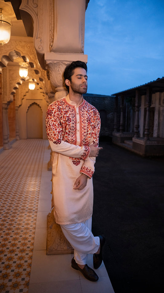 Man in traditional outfit standing in a decorative architectural setting