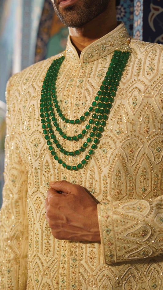 Man wearing a beige embroidered sherwani with green beads