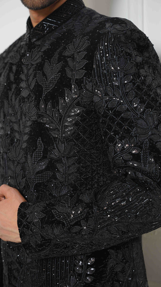 Black embroidered garment with intricate designs on a plain background