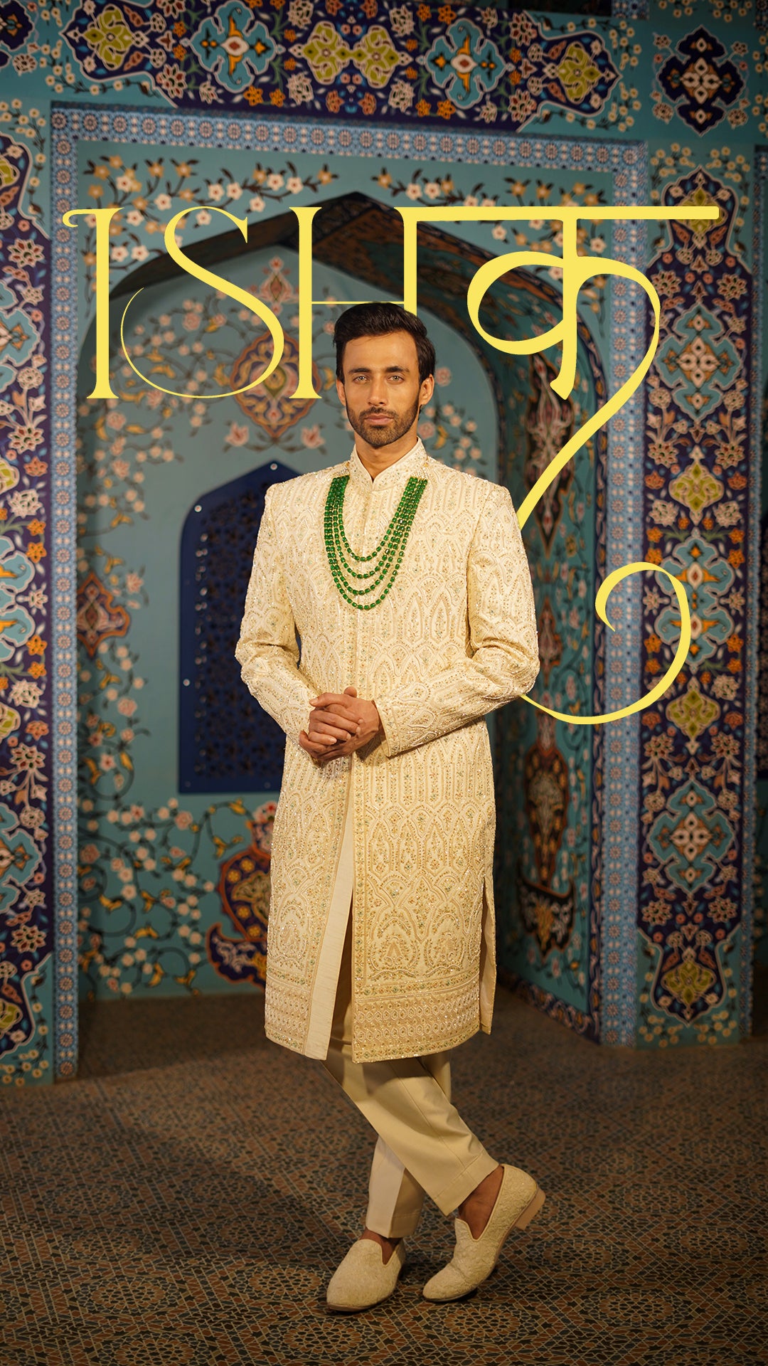 Man in traditional cream sherwani with green accessories against a decorative background